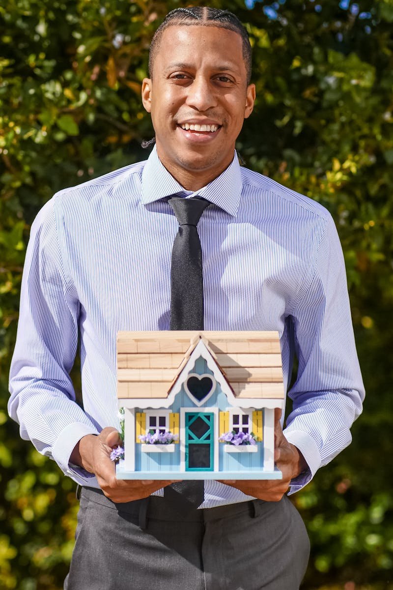 Professional realtor holding a small house model, symbolizing real estate and new home purchases.
